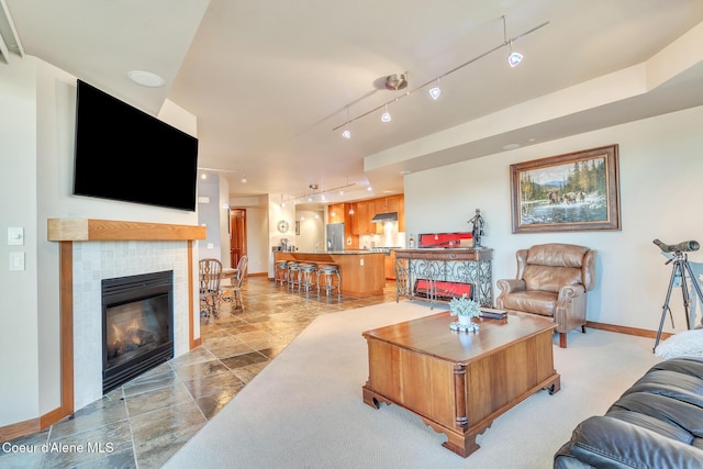 living room with track lighting, baseboards, and a tiled fireplace