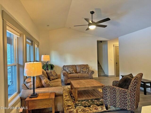 living room with baseboards, lofted ceiling, ceiling fan, stairway, and wood finished floors