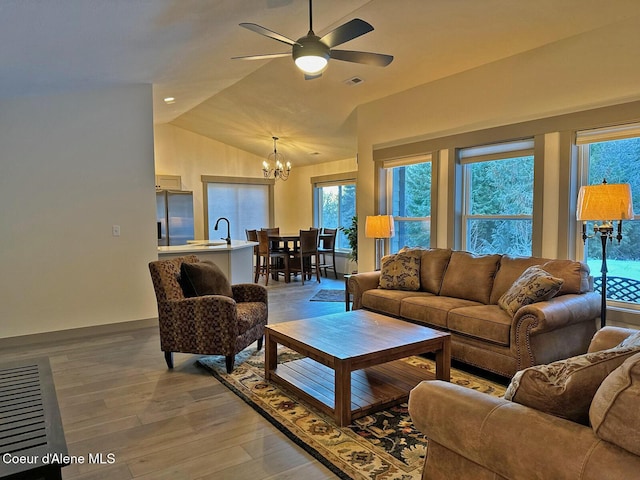 living area featuring light wood-style flooring, visible vents, vaulted ceiling, and ceiling fan with notable chandelier