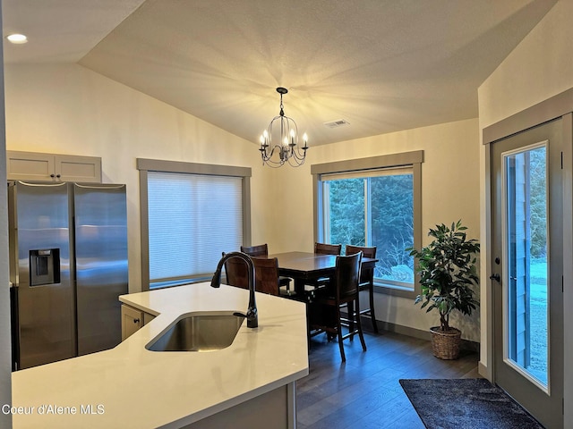 kitchen with dark wood finished floors, lofted ceiling, light countertops, stainless steel refrigerator with ice dispenser, and a sink