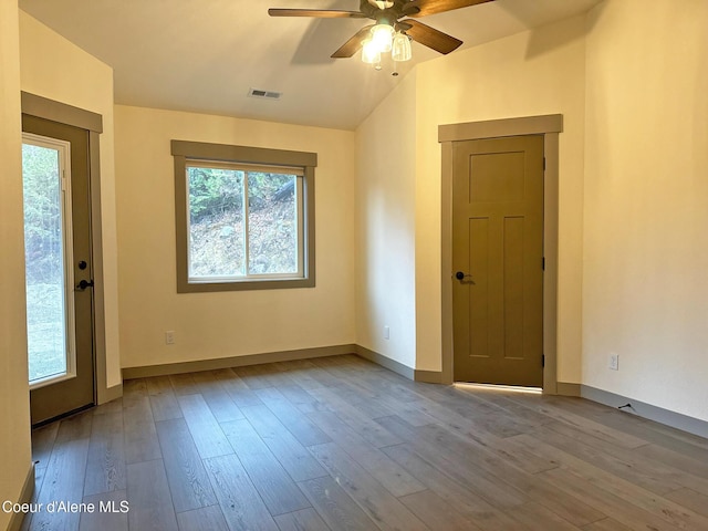 spare room featuring lofted ceiling, wood finished floors, a ceiling fan, visible vents, and baseboards