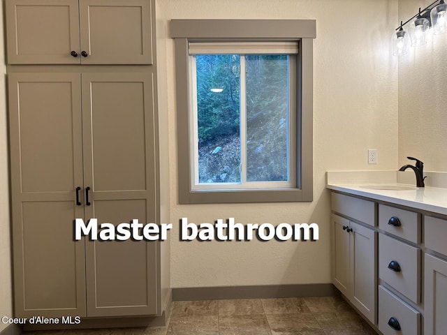 bathroom featuring a textured wall, vanity, and baseboards