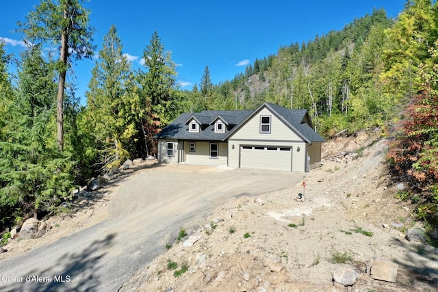 view of front of property with dirt driveway and a wooded view