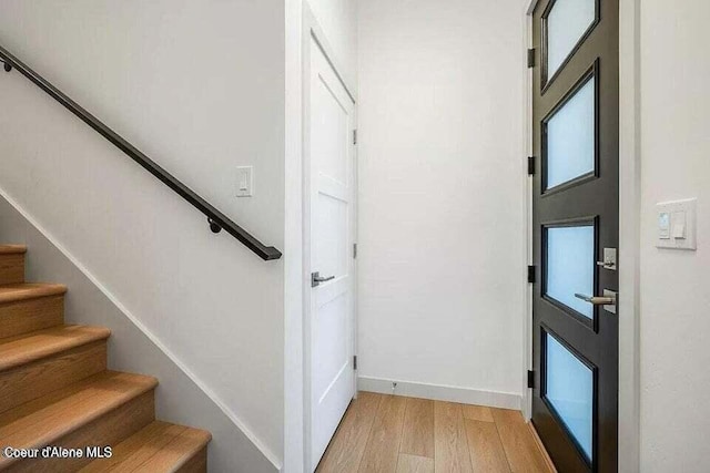 foyer entrance with stairway, light wood-style flooring, and baseboards