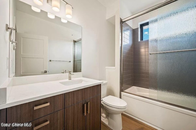 bathroom with enclosed tub / shower combo, vanity, toilet, and wood finished floors