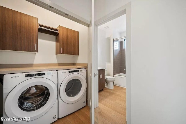 laundry room featuring light wood-type flooring, independent washer and dryer, and cabinet space