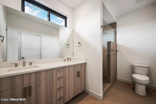 bathroom with toilet, a sink, baseboards, double vanity, and a stall shower