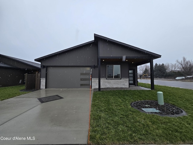 modern home featuring a front yard, stone siding, driveway, and an attached garage