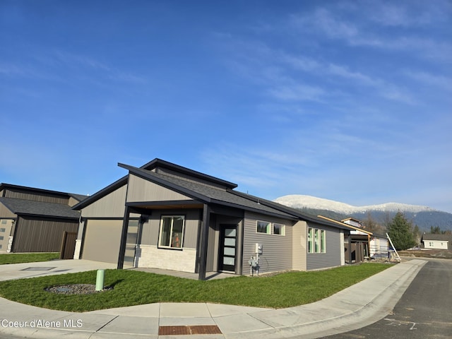 view of front of property featuring a front lawn, concrete driveway, a mountain view, and an attached garage