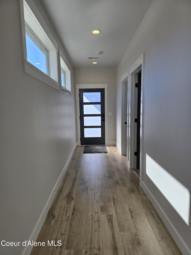 doorway featuring visible vents, baseboards, wood finished floors, and recessed lighting