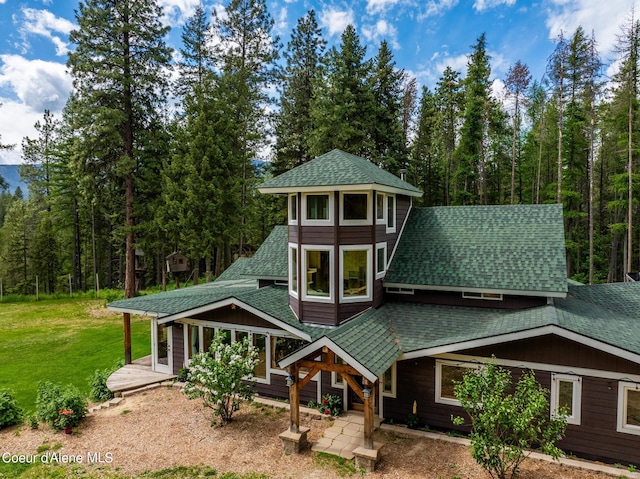 view of front of house featuring roof with shingles and a front lawn