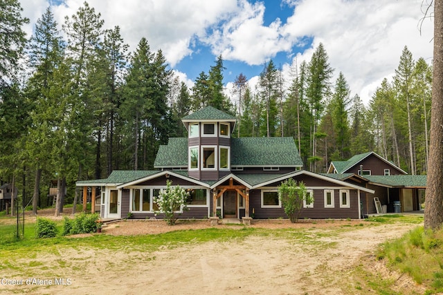 view of front facade with roof with shingles and dirt driveway