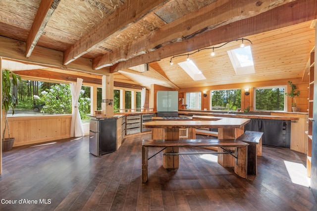 interior space featuring vaulted ceiling with skylight, wood walls, dark wood finished floors, and wood ceiling