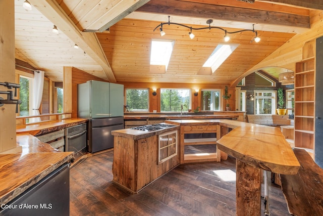 kitchen with lofted ceiling with skylight, butcher block counters, dark wood-style flooring, and freestanding refrigerator