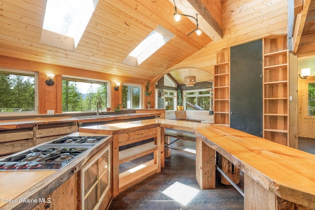 kitchen featuring wooden ceiling, lofted ceiling with skylight, butcher block countertops, stovetop with downdraft, and a sink