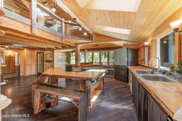 kitchen with arched walkways, wooden ceiling, a sink, wooden counters, and freestanding refrigerator