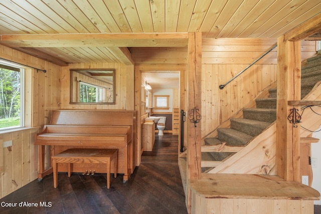 living area featuring wooden walls, wood ceiling, stairway, beamed ceiling, and dark wood finished floors