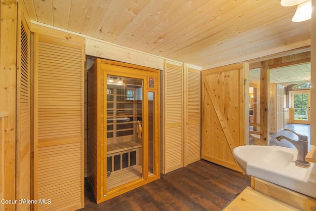 bathroom featuring a sink, wood walls, wood ceiling, and wood finished floors