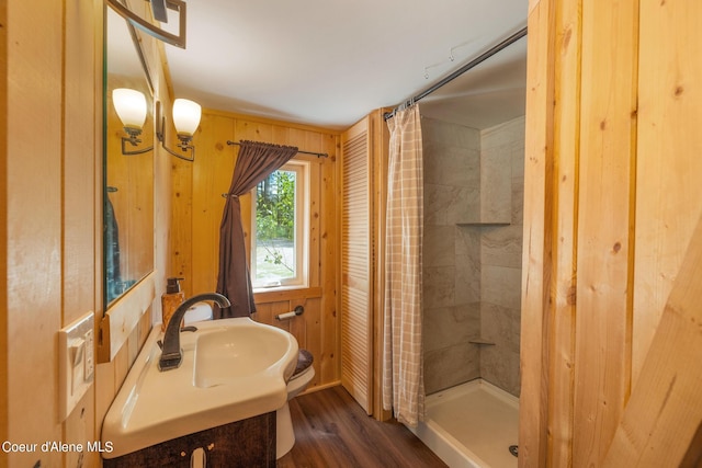 bathroom with a shower stall, wooden walls, and wood finished floors