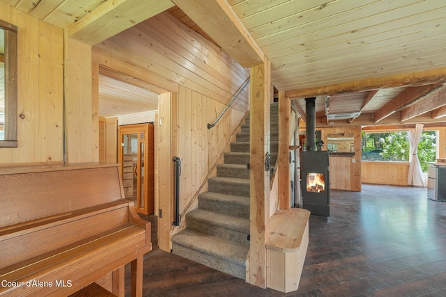 stairs featuring a wood stove, wood ceiling, wooden walls, and hardwood / wood-style floors