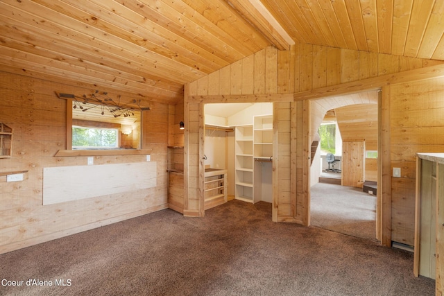 carpeted empty room with vaulted ceiling with beams, wood ceiling, and wooden walls