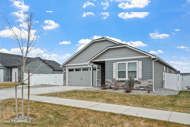 view of front of property featuring driveway, stone siding, an attached garage, a gate, and fence