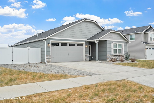 craftsman house featuring a garage, fence, driveway, stone siding, and a gate