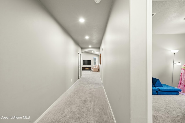 corridor featuring carpet, arched walkways, recessed lighting, a textured ceiling, and baseboards