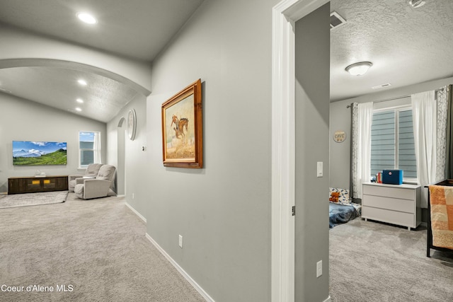 hallway featuring baseboards, arched walkways, vaulted ceiling, carpet flooring, and recessed lighting