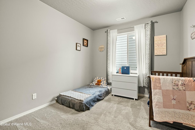 carpeted bedroom featuring baseboards, visible vents, and a textured ceiling