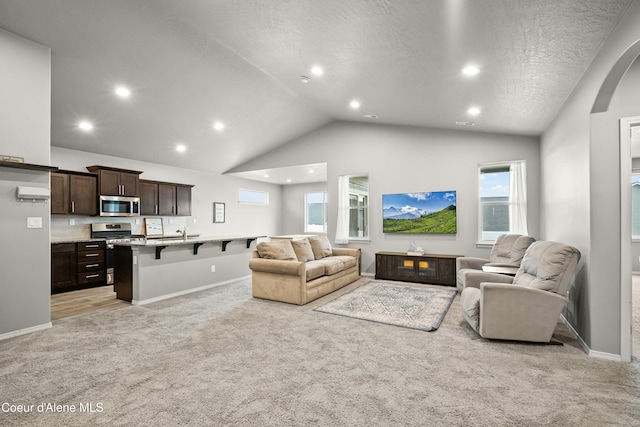 living room with light carpet, baseboards, arched walkways, a textured ceiling, and recessed lighting