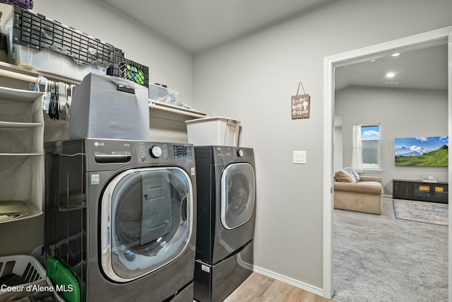 clothes washing area with carpet floors, laundry area, baseboards, and washer and clothes dryer