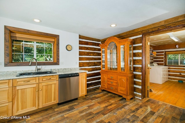 kitchen with dishwasher, washing machine and clothes dryer, a sink, and a wealth of natural light