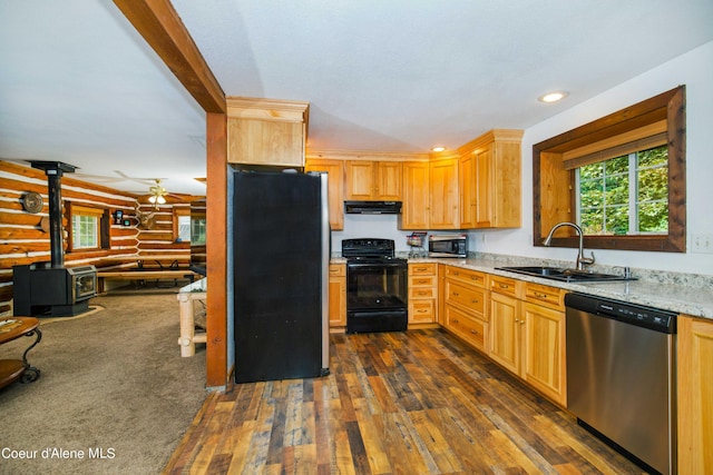 kitchen featuring dark wood finished floors, appliances with stainless steel finishes, a wood stove, a sink, and exhaust hood