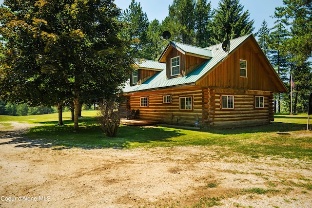 view of property exterior with metal roof, log exterior, and a yard