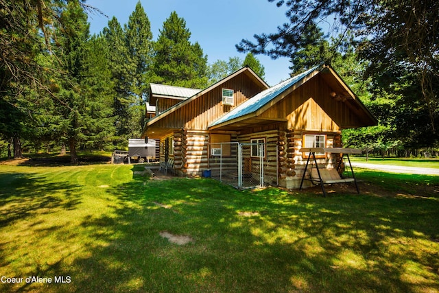 rear view of property with metal roof, log exterior, and an outdoor structure