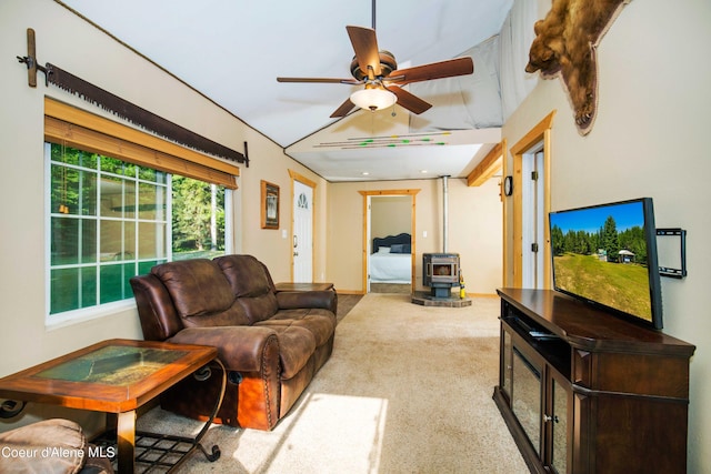 carpeted living room featuring a wood stove and ceiling fan