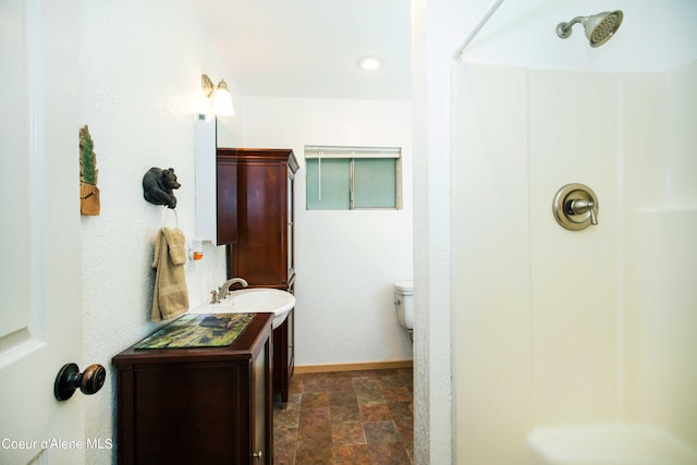 full bath with a shower, stone finish floor, vanity, and baseboards