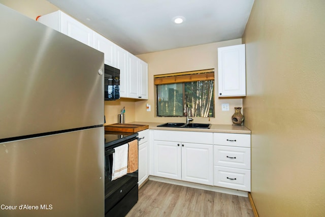 kitchen with white cabinetry, a sink, light wood-style flooring, and black appliances