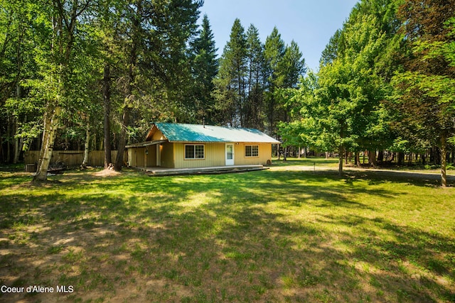 rear view of property featuring metal roof, a lawn, and fence