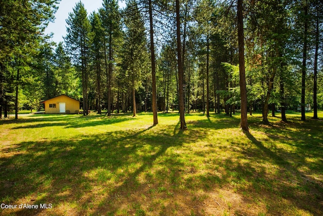 view of yard featuring a garage, a wooded view, and an outdoor structure