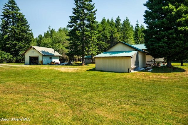 view of yard featuring a detached garage, a pole building, and an outbuilding