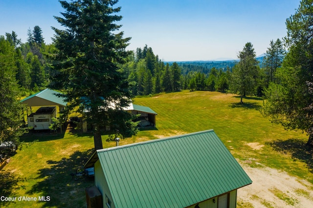 surrounding community with a carport, a lawn, and a wooded view