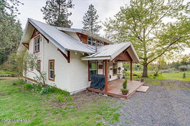 rear view of house featuring metal roof, a chimney, and a lawn