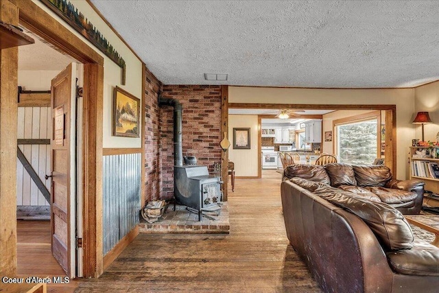 living area featuring a textured ceiling, a wood stove, and light wood-style floors