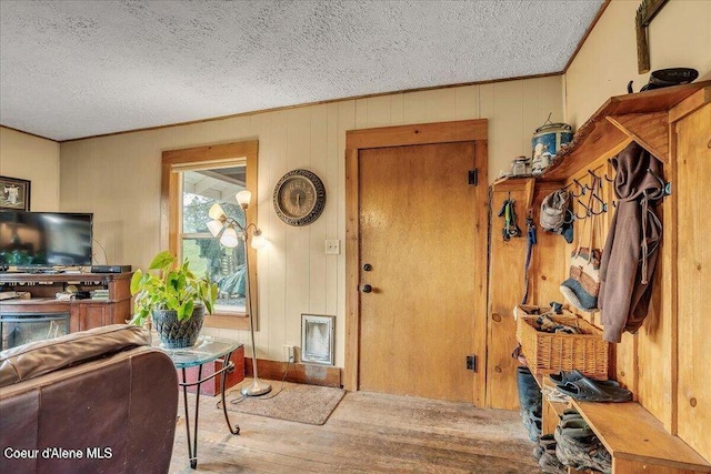 entryway with a textured ceiling, ornamental molding, and wood-type flooring