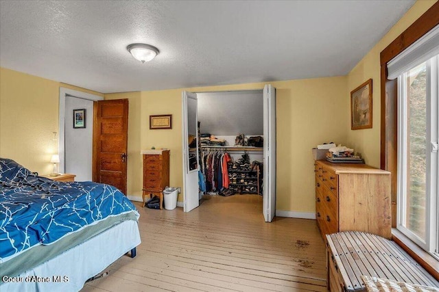 bedroom featuring a textured ceiling, a closet, hardwood / wood-style flooring, and baseboards