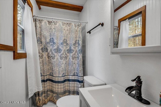 bathroom featuring a shower with shower curtain, a textured wall, vanity, and toilet