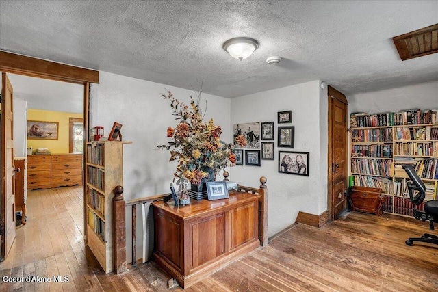 office with wood-type flooring and a textured ceiling