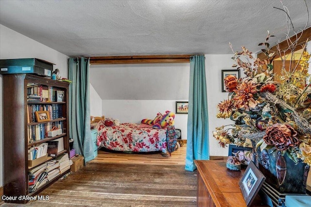 bedroom featuring lofted ceiling, a textured ceiling, and wood finished floors